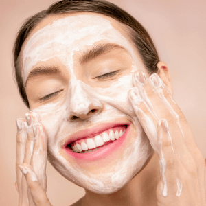 Woman smiling with a bubbly cleansing foam on her face, showcasing Best Natural Facial Care.