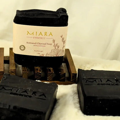 MIARA Essence activated charcoal soap on a wooden block with a white background